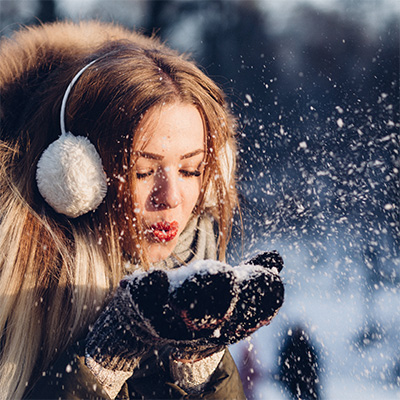 Femme en manteau d'hiver soufflant dans de la neige